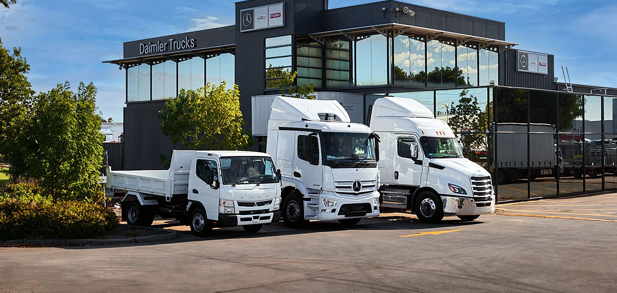 White Fuso, Mercedes Benz and Freightliner trucks parked outside a Dealership