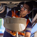 A mechanic performing maintenance on the underside of a truck