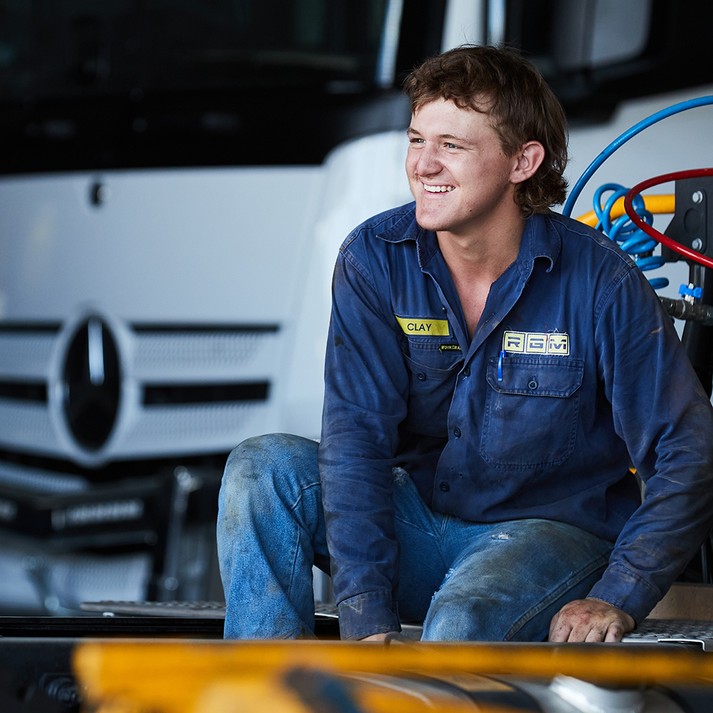 A mechanic in their workshop with a white Mercedes-Benz truck in the background