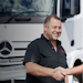 Two people shaking hands in front of a white Mercedes-Benz truck